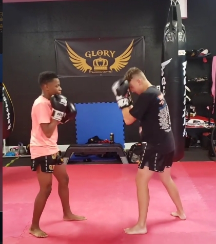 Students practising Muay Thai partner drills under the Glory banner